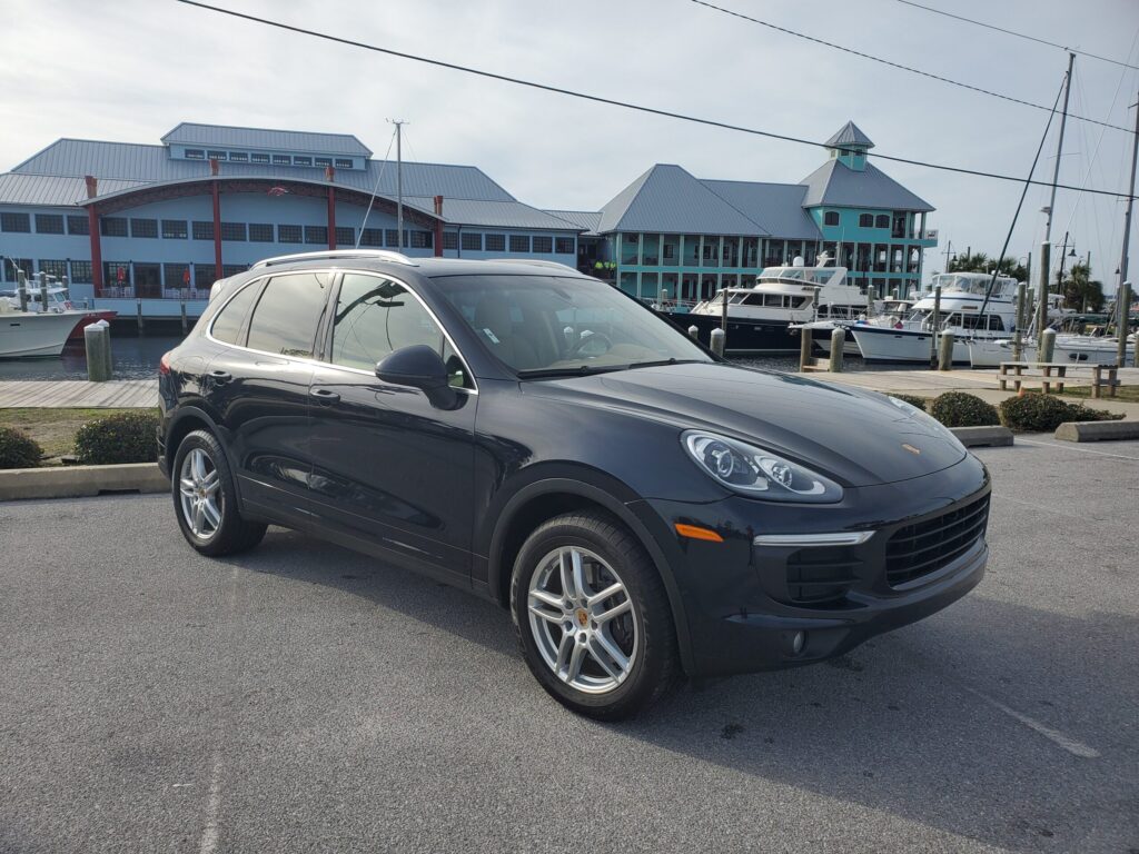 Black luxury SUV parked near waterfront buildings on a clear day.