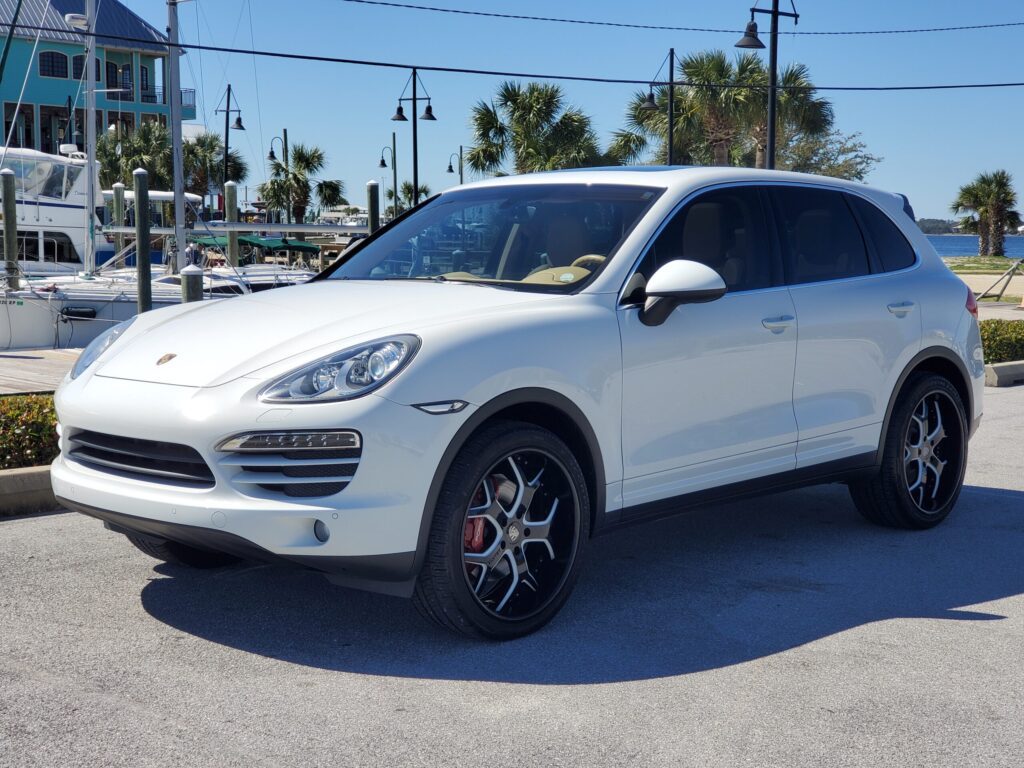 White luxury SUV parked on a sunny street with palm trees.